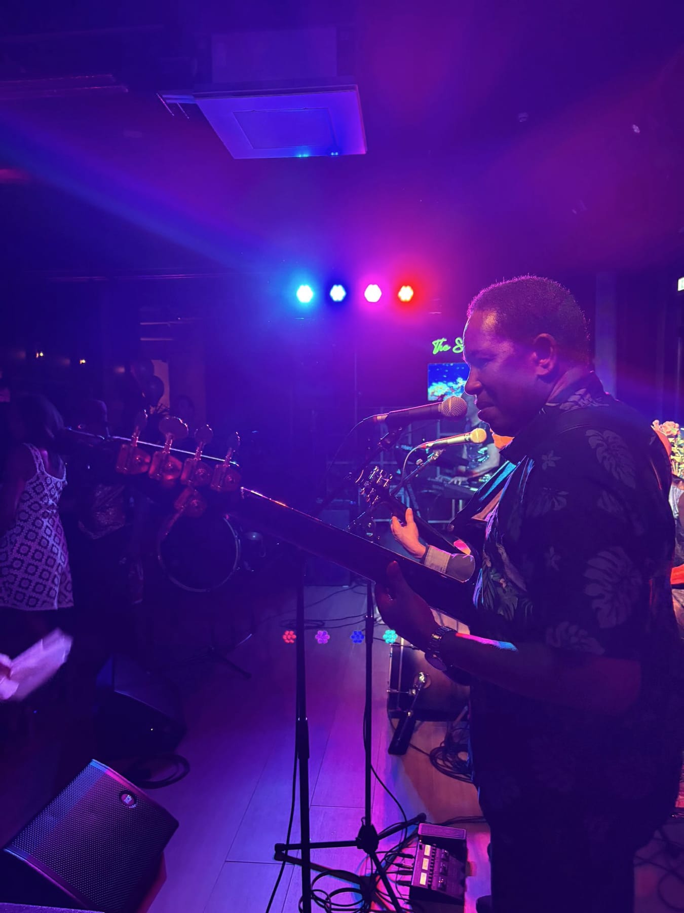 Liveband op het podium van The Scene tijdens een feestavond, met de neonletters aan de wand